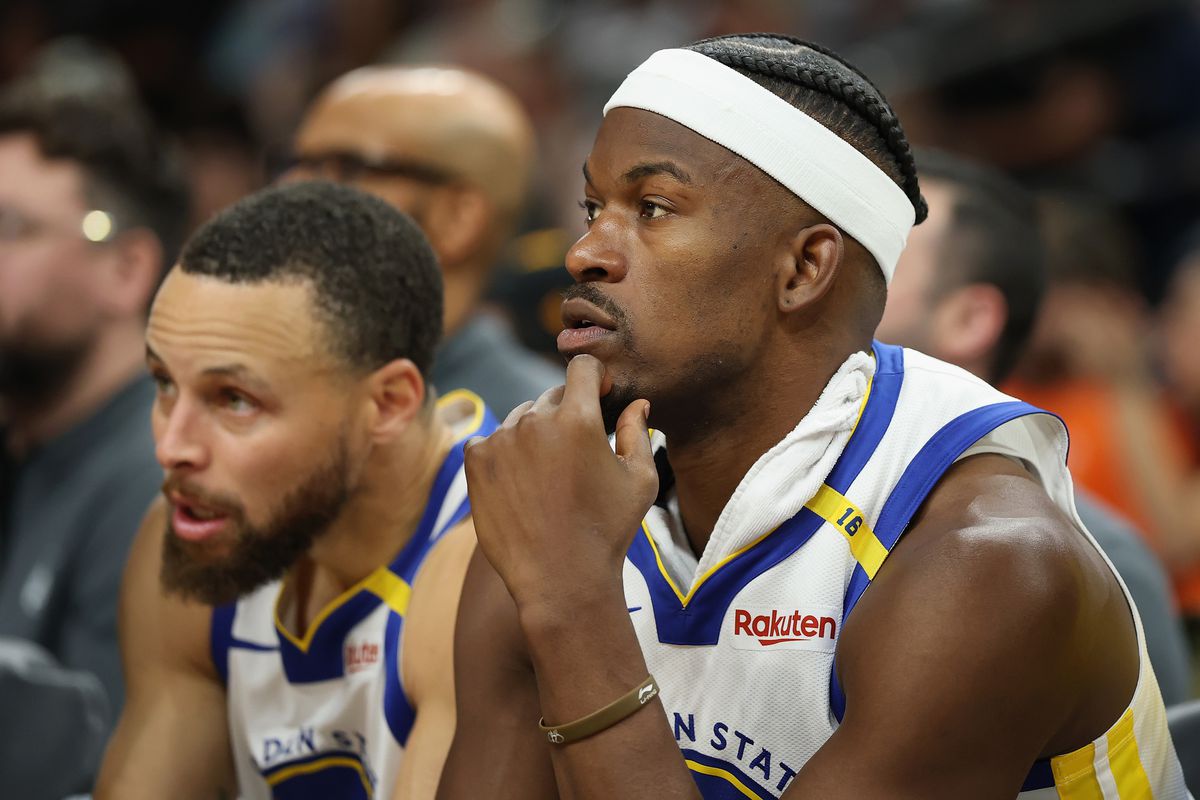 Jimmy Butler III #10 and Stephen Curry #30 of the Golden State Warriors watch from the bench during the second half of the NBA game against the Phoenix Suns at PHX Arena 