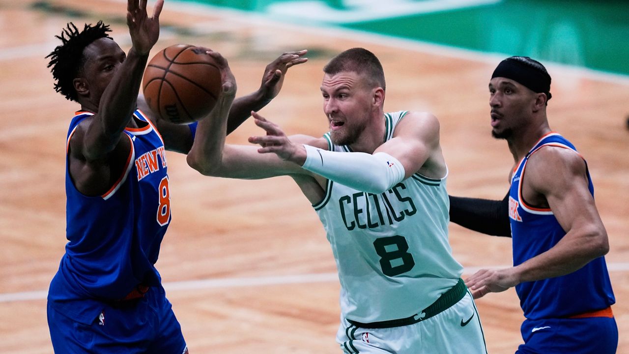 Boston Celtics center Kristaps Porzingis (8) passes the ball while pressured by the New York Knicks during the first half of Game 1 of an NBA basketball second-round playoff series Monday, May 5, 2025, in Boston. (AP Photo/Charles Krupa)