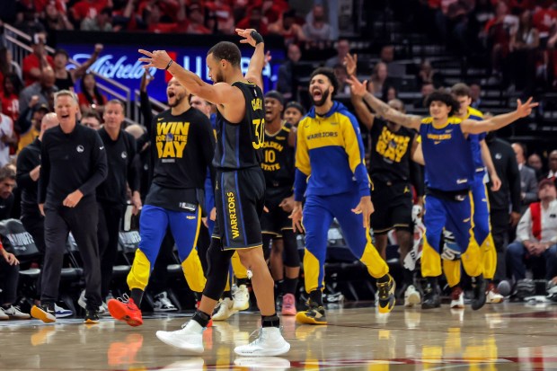 Golden State Warriors players react to Buddy Hield's (7) first quarter buzzer-beater against the Houston Rockets in Game 7 of an NBA basketball first-round playoff series in Houston, Sunday, May 4, 2025. (Carlos Avila Gonzalez/San Francisco Chronicle via AP)