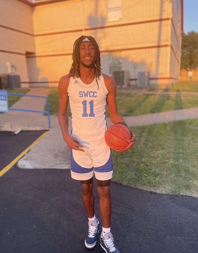 Basketball player in SWCC jersey and shorts holding a basketball.