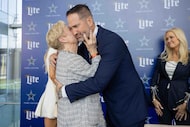 Dallas Cowboys head coach Brian Schottenheimer (right) receives a kiss on the cheek from his...
