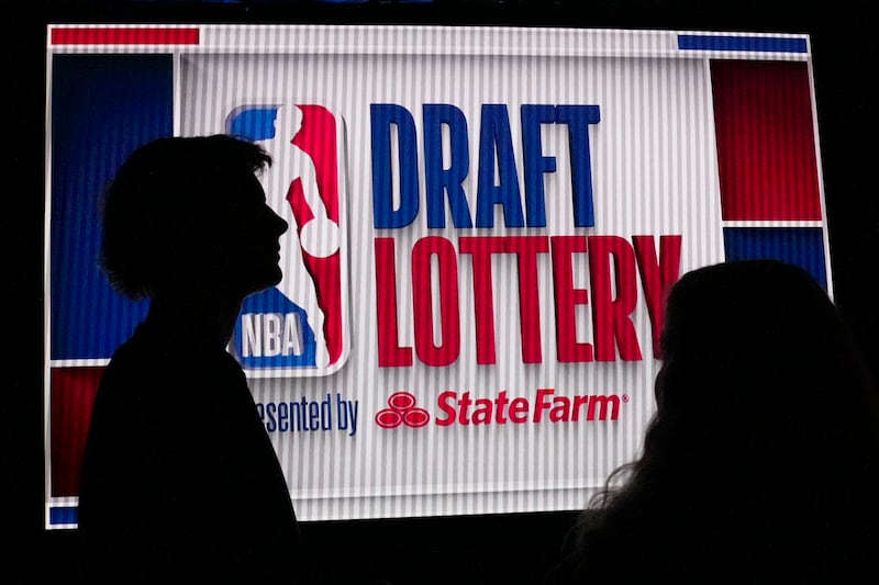 NBA basketball draft prospect Johnny Furphy, left, looks at the draft lottery order in front of a draft lottery sign before the draft lottery in Chicago, Sunday, May 12, 2024.