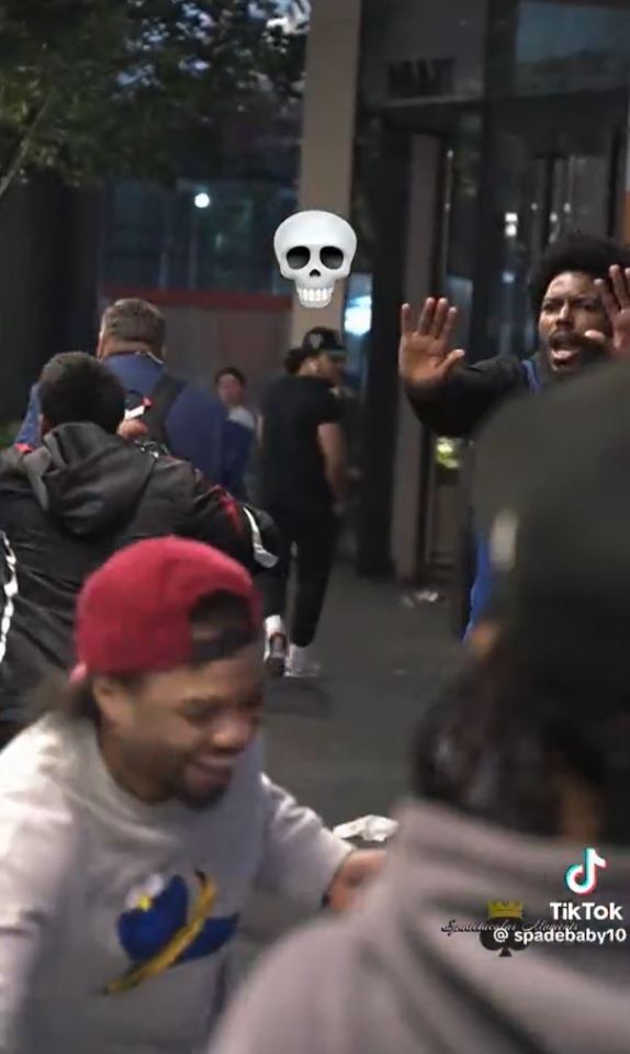 A group of people outside at night, one person raises their hands.