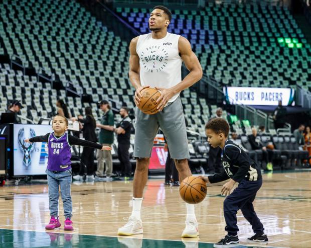 Milwaukee Bucks forward Giannis Antetokounmpo, center, warm up with his...