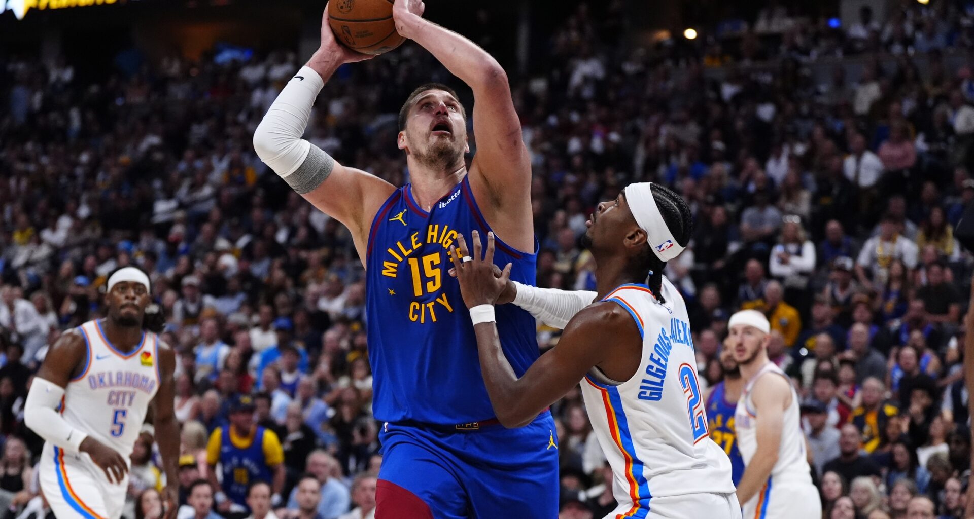 Nuggets superstar Nikola Jokic goes up with a shot over Shai Gilgeous-Alexander during the 2024-25 NBA Playoffs.