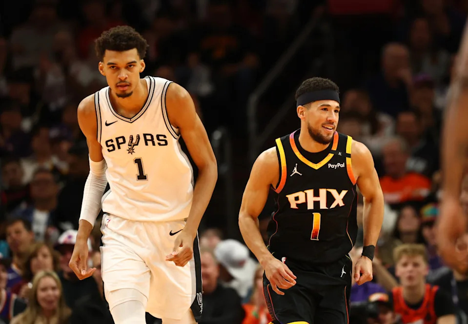 Dec 3, 2024; Phoenix, Arizona, USA; Phoenix Suns guard Devin Booker (right) against San Antonio Spurs center Victor Wembanyama in the first half of an NBA Cup game at Footprint Center.© Mark J. Rebilas-Imagn Images