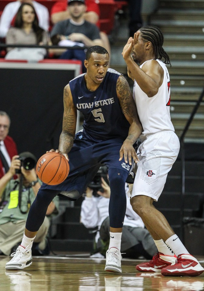 Utah State Aggies basketball player Jarred Shaw dribbling the ball.