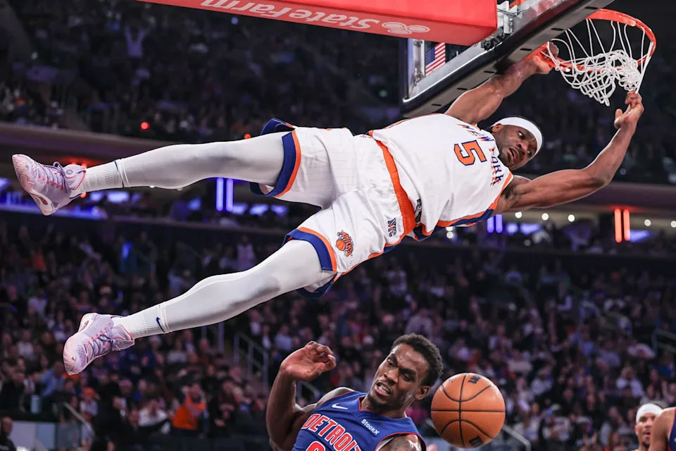 Dec 7, 2024; New York, New York, USA; New York Knicks forward Precious Achiuwa (5) hangs on the rim after a dunk against the Detroit Pistons during the second half at Madison Square Garden. Mandatory Credit: Vincent Carchietta-Imagn Images