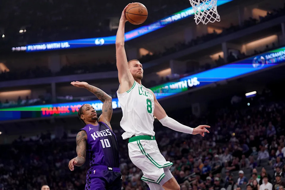 Mar 24, 2025; Sacramento, California, USA; Boston Celtics forward Kristaps Porzingis (8) dunks the ball in front of Sacramento Kings guard DeMar DeRozan (10) in the first quarter at the Golden 1 Center. Mandatory Credit: Cary Edmondson-Imagn Images