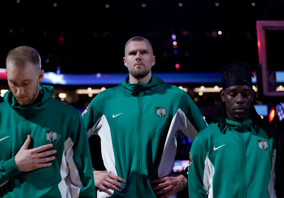 Boston, MA - June 9: Boston Celtics center Kristaps Porzingis, middle, stands during the national anthem with forward Sam Hauser, left, and guard Jrue Holiday before Game 2 of the 2024 NBA Finals. (Photo by Danielle Parhizkaran/The Boston Globe via Getty Images)Boston Globe&sol;Getty Images