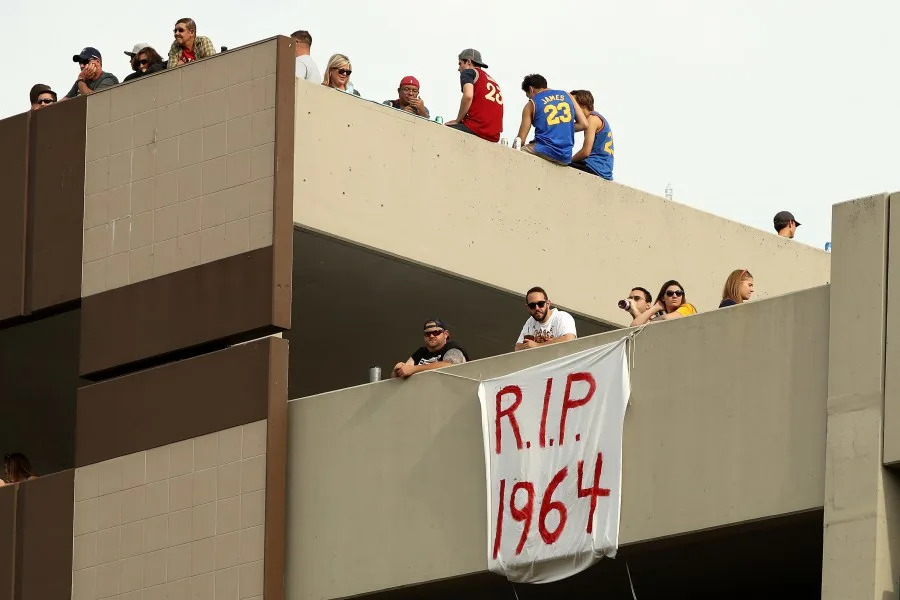 Fans look on from a parking garage near a sign reading “R.I.P. 1964” during the Cleveland Cavaliers 2016 NBA Championship victory parade and rally on June 22, 2016 in Cleveland, Ohio. (Photo by Mike Lawrie/Getty Images)