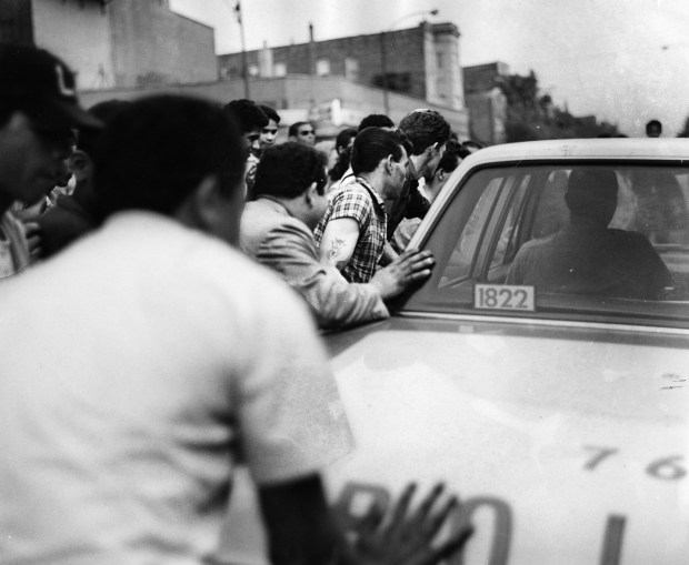 A crowd pushes a squad car in an apparent attempt...