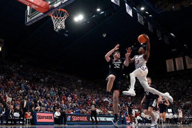 Kansas guard Elmarko Jackson (13) shoots over UConn center Donovan Clingan (32) during the first half of an NCAA college basketball game Friday, Dec. 1, 2023, in Lawrence, Kan. (AP Photo/Charlie Riedel)