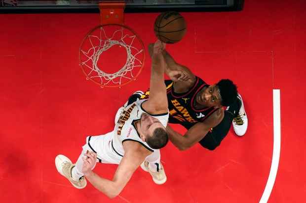 Denver Nuggets center Nikola Jokic (15) and Atlanta Hawks forward De'Andre Hunter (12) battle for a rebound in the first half of an NBA basketball game, Sunday, Dec. 8, 2024, in Atlanta. (AP Photo/John Bazemore)