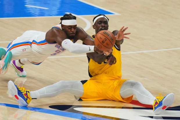 Oklahoma City Thunder guard Luguentz Dort, left, dives over Indiana...