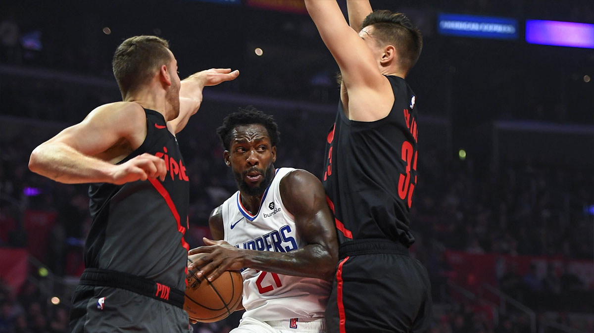 Los Angeles Clippers guard Patrick Beverley (21) passes the ball between Portland Trail Blazers forward Al-Farouq Aminu (left) and Trail Blazers forward Zach Collins (33) during the second quarter at Staples Center.