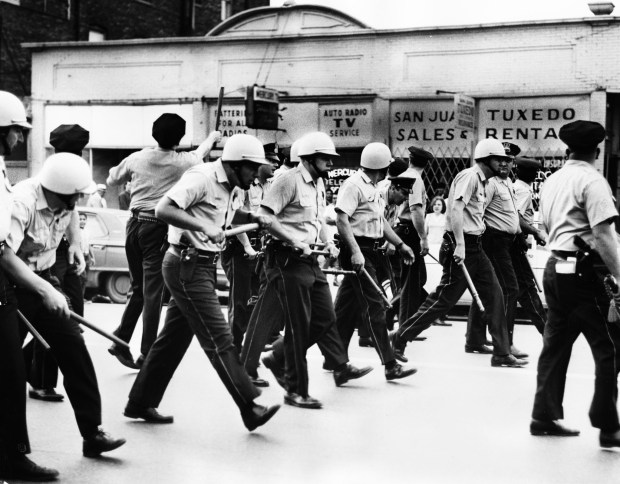 Chicago police officers duck as people throw bottles and stones...