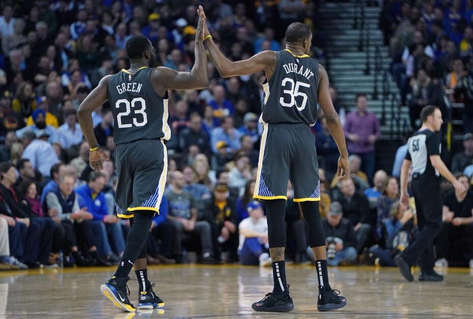 Draymond Green and Kevin Durant high five, picture from behind. Grey Warriors jerseys