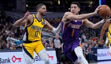 Devin Booker #1 of the Phoenix Suns dribbles the ball while being guarded by Tyrese Haliburton #0 o...