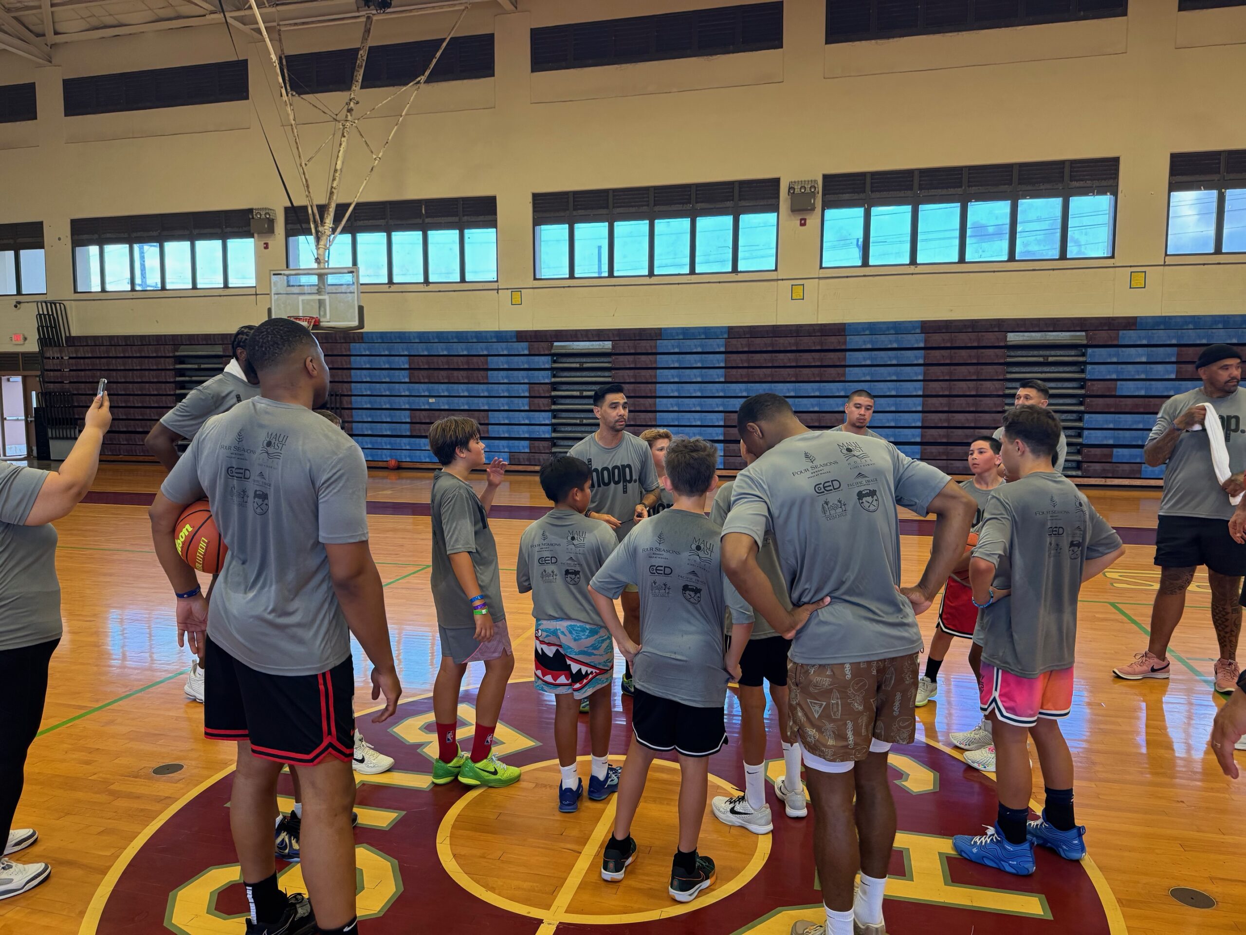 Camp Director Cody Tesoro (middle, facing camera) addresses the coaches and campers at the Just Hoop Maui camp on Friday event. HJI / ROB COLLIAS photo