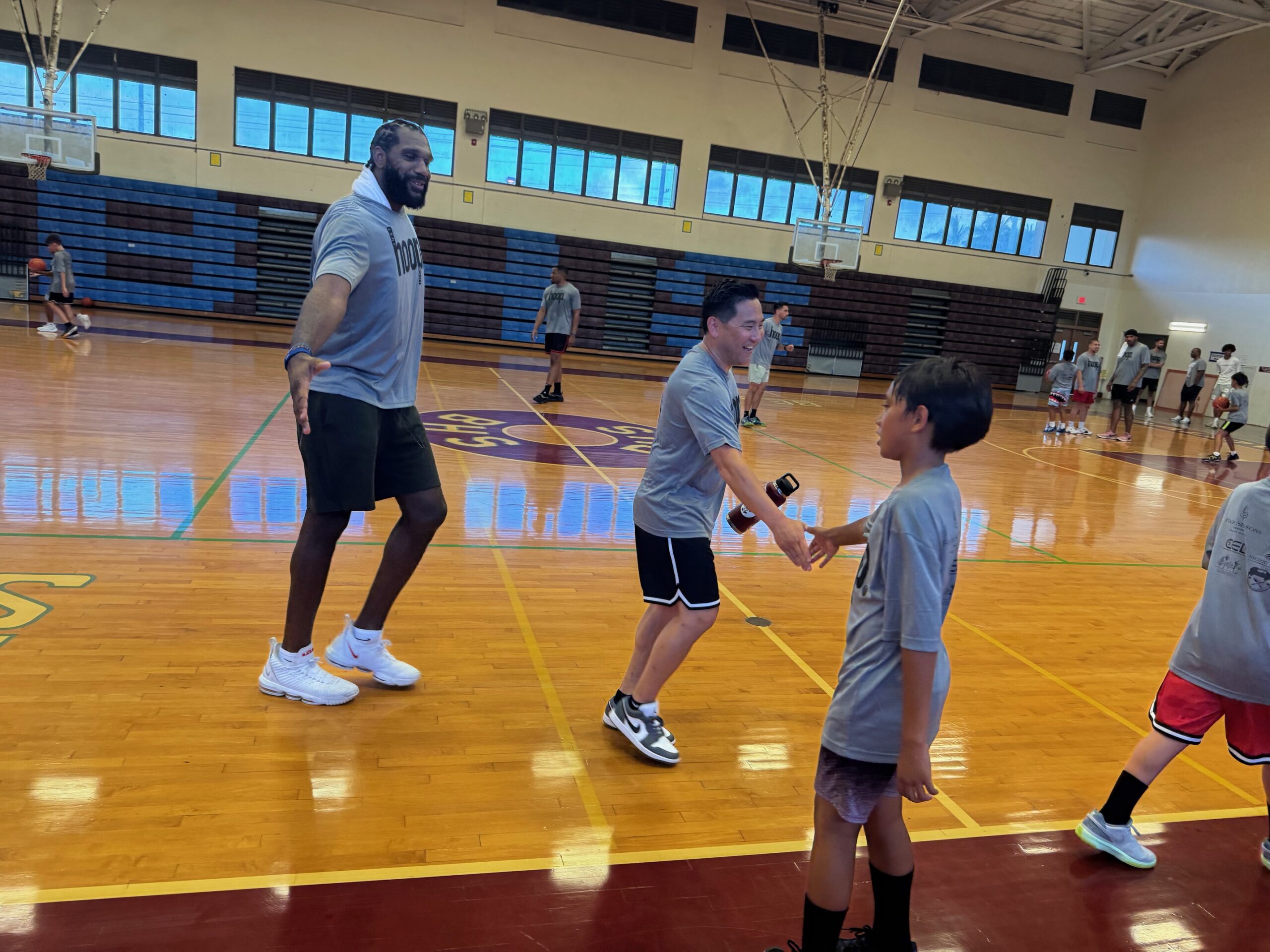 JJ Ulufale, an 11-year-old sixth grader at Maui Waena Intermediate School, daps Casey Kushiyama as Greg Oden prepares to dap Ulufale as well Friday at the Just Hoop Maui basketball camp at the Baldwin High School gym. HJI / ROB COLLIAS photo