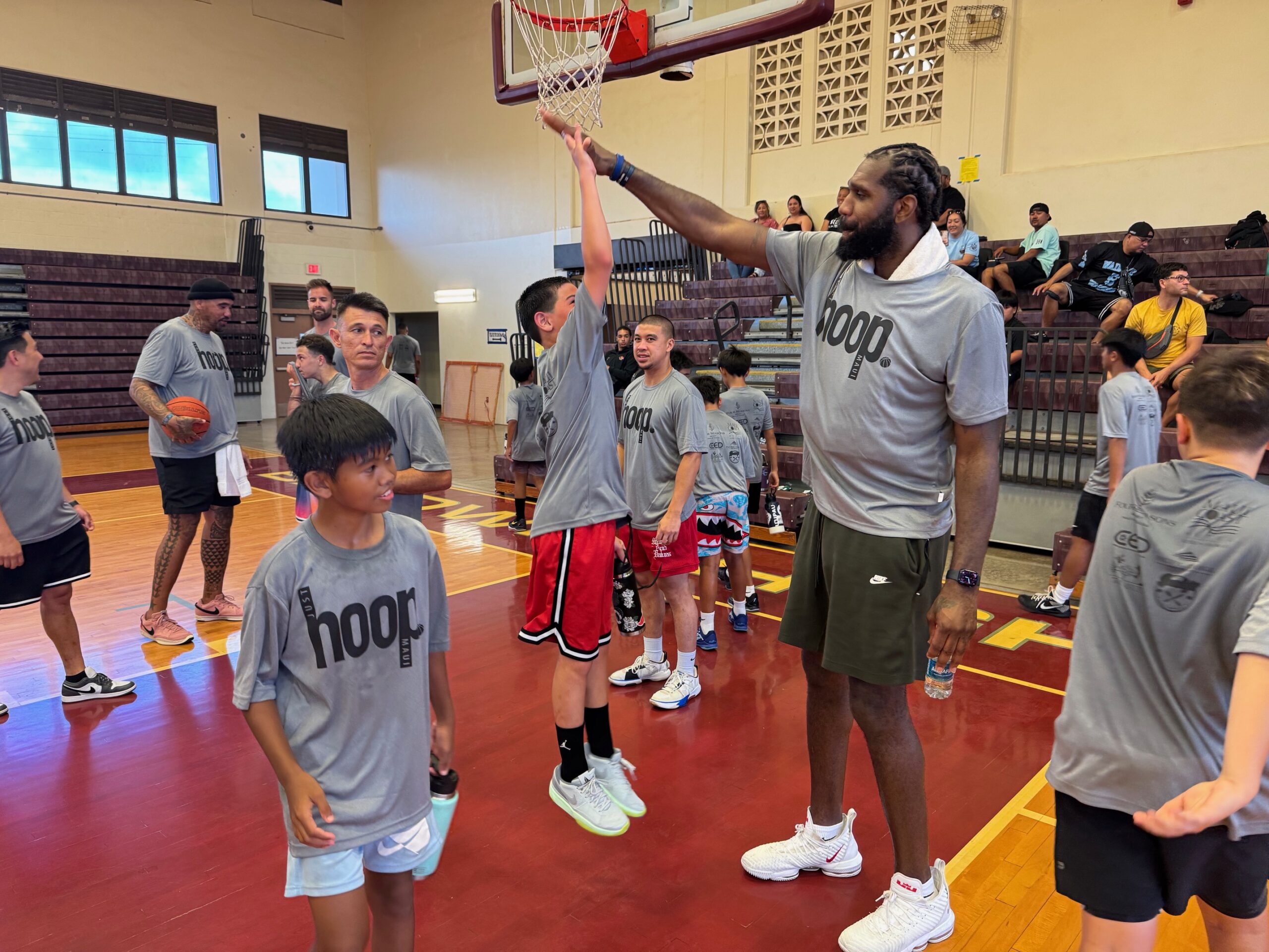 Keo Kushiyama (red shorts), a 10-year-old from University Place, Wash., leaps to high five Greg Oden, a 7-foot tall former No. 1 NBA draft pick, at the Just Hoop Maui basketball camp Saturday at the Jon Garcia Gym at Baldwin High School. HUI / ROB COLLIAS photo