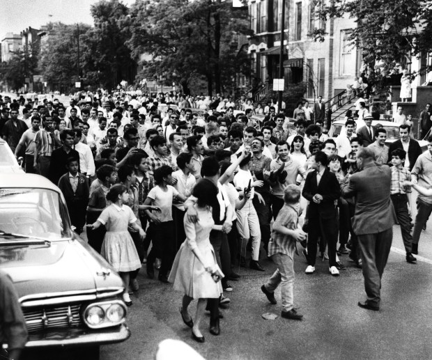 A crowd marches through the streets of Humboldt Park as...