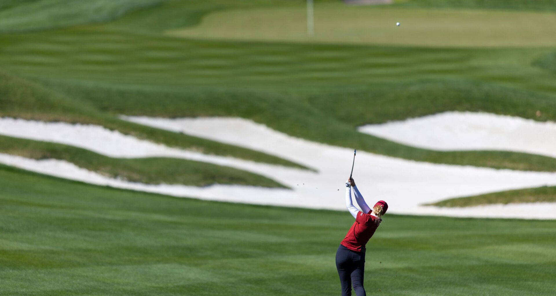 Ball flys as golfer follows through.