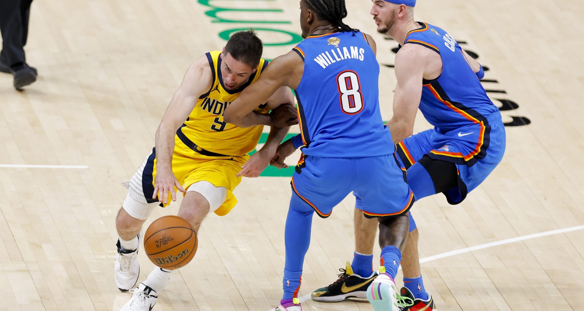 Indiana Pacers guard T.J. McConnell (9) drives to the basket past Oklahoma City Thunder forward Jalen Williams (8) and guard Alex Caruso (9) during the fourth quarter of game two of the 2025 NBA Finals at Paycom Center.