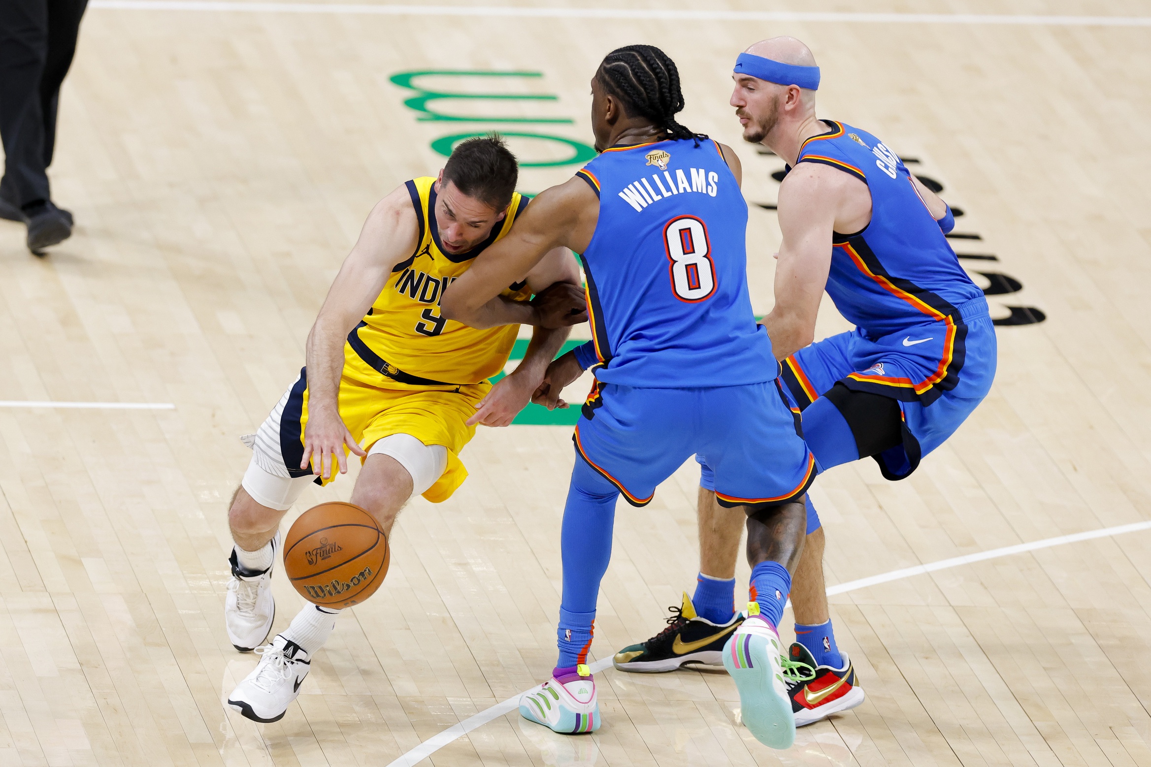 Indiana Pacers guard T.J. McConnell (9) drives to the basket past Oklahoma City Thunder forward Jalen Williams (8) and guard Alex Caruso (9) during the fourth quarter of game two of the 2025 NBA Finals at Paycom Center.