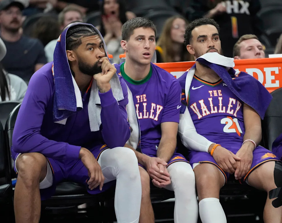Phoenix Suns center Nick Richards (left) and guards Collin Gillespie (center) and Tyus Jones (21) watch from the bench during the fourth quarter against the Houston Rockets at PHX Arena in Phoenix on March 30, 2025.