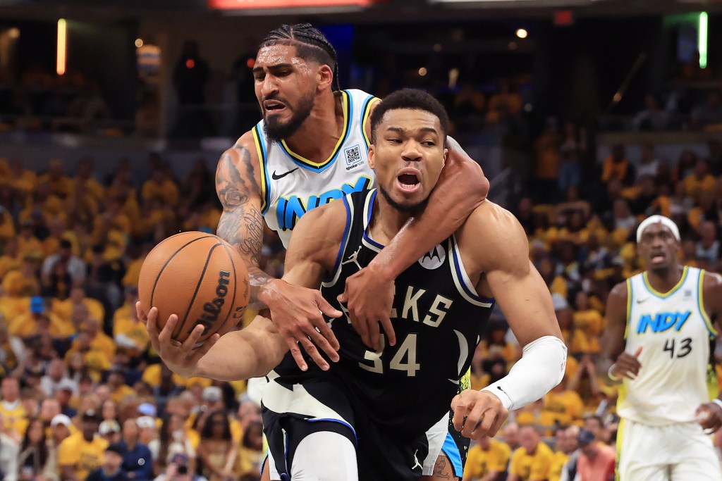 Milwaukee Bucks player #34 dribbling the ball, guarded by an Indiana Pacers player.