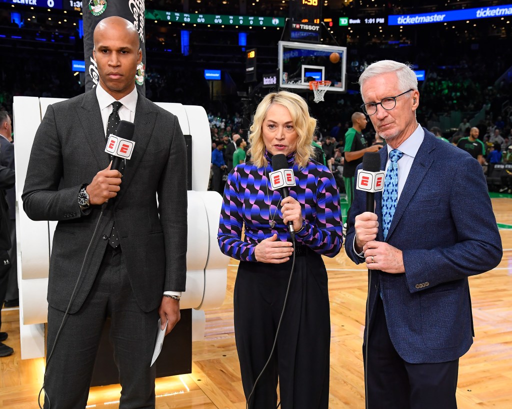 Three sportscasters holding microphones at a basketball game.