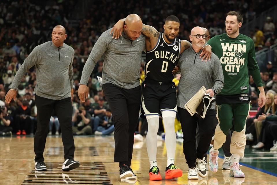 Injured Milwaukee Bucks player Damian Lillard being helped off the court.