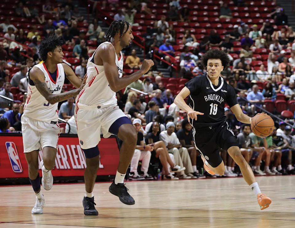 LAS VEGAS, NEVADA - JULY 13: Nolan Traore #19 of the Brooklyn Nets drives against AJ Johnson (L) #5 and Alex Sarr #20 of the Washington Wizards in the first half of a 2025 NBA Summer League game at the Thomas & Mack Center on July 13, 2025 in Las Vegas, Nevada. NOTE TO USER: User expressly acknowledges and agrees that, by downloading and or using this photograph, User is consenting to the terms and conditions of the Getty Images License Agreement. (Photo by Ethan Miller/Getty Images)