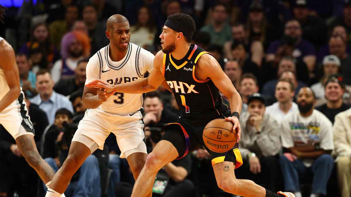 Phoenix Suns guard Devin Booker (1) against San Antonio Spurs guard Chris Paul (3) in the first half of an NBA Cup game at Footprint Center.