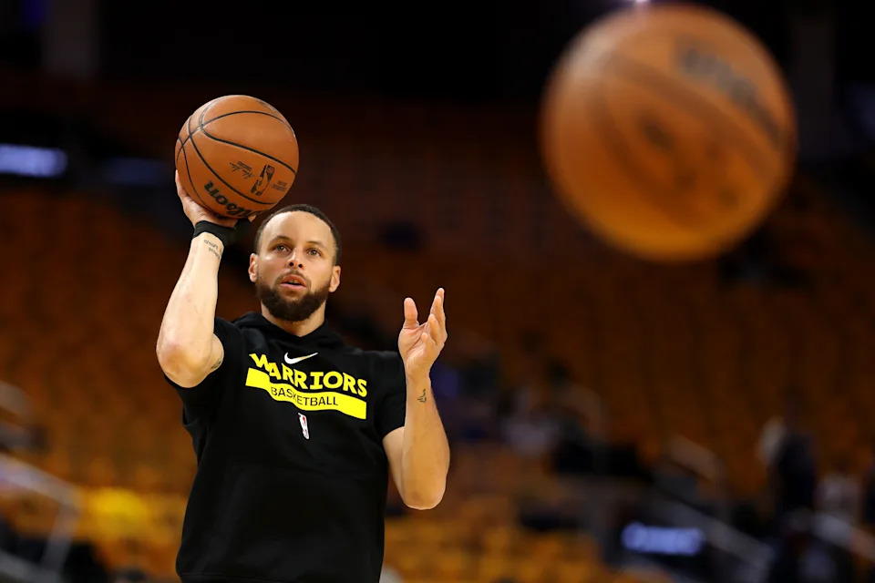 Basketball player on court wearing a team shirt, practicing shooting hoops