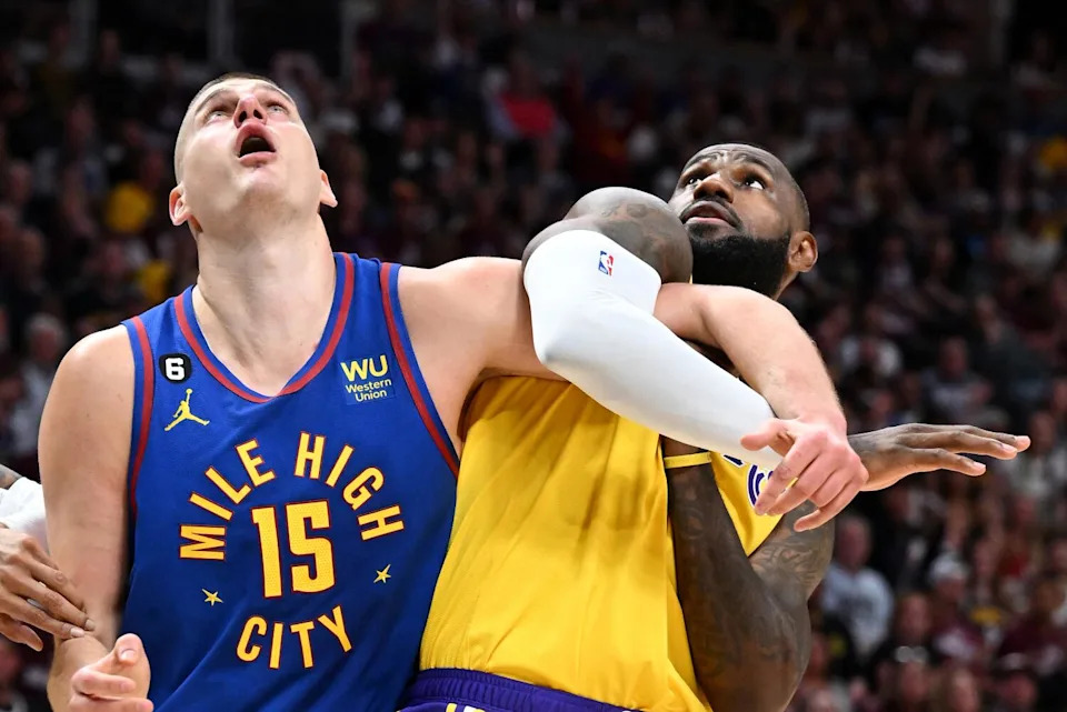 Lakers star LeBron James, right, and Nuggets center Nikola Jokic entangle their arms while battling for rebound position.
