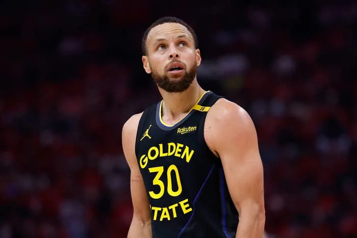 Basketball player in a Golden State jersey looks upward on the court