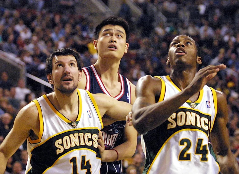 SEATTLE, UNITED STATES: Houston Rocket sensation Yao Ming (C) is blocked out on a rebound opportunity by Seattle Supersonic Pedrag Drobnjak (L) and Desmond Mason during second quarter of play of their game in Seattle, 29 November of 2002. AFP PHOTO (Photo credit should read DAN LEVINE/AFP via Getty Images)