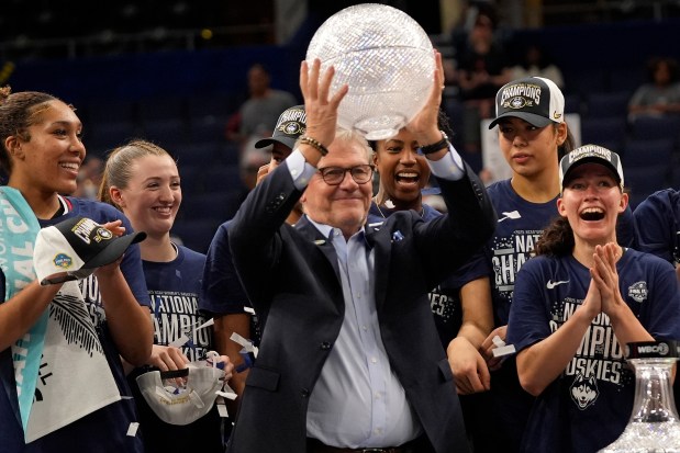 Geno Auriemma, center, holds up the coaches' trophy after the Huskies defeated South Carolina in the national championship game at the Final Four of the women's NCAA college basketball final. He's reloaded for a run at title No. 13. (AP Photo/Chris O'Meara)
