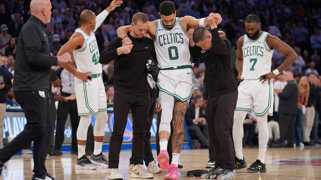 Trainers help Boston Celtics' Jayson Tatum (0) off the court after he was injured during the second half of Game 4 in the Eastern Conference semifinals of the NBA basketball playoffs against the New York Knicks, May 12, 2025, in New York. (AP Photo/Frank Franklin II, File)