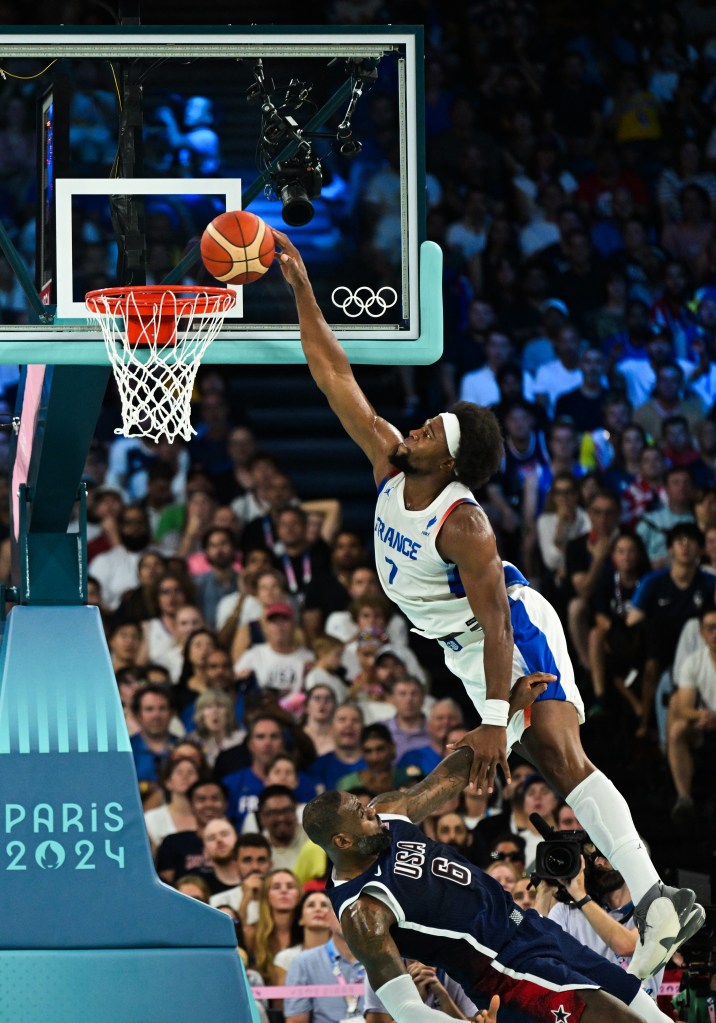 France's #07 Guerschon Yabusele dunks the ball over USA's #06 LeBron James in the men's Gold Medal basketball game at the 2024 Olympics.
