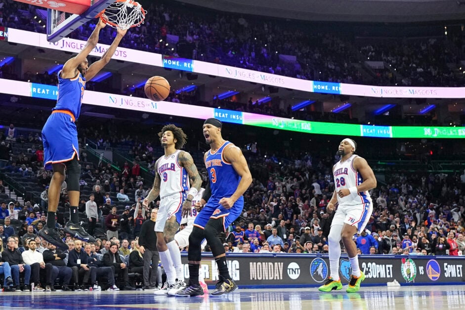 Mikal Bridges #25 of the New York Knicks dunks the ball in overtime as teammate Josh Hart #3 reacts and Kelly Oubre Jr. #9 and Guerschon Yabusele #28 of the Philadelphia 76ers look on at the Wells Fargo Center on January 15, 2025 in Philadelphia, Pennsylvania.