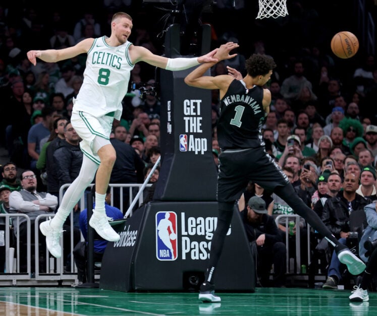 Kristaps Porzingis #8 of the Boston Celtics and Victor Wembanyama #1 of the San Antonio Spurs rebound during the second half of the NBA game at the TD Garden.