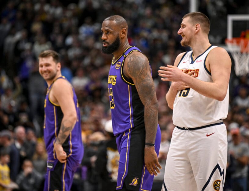 Nikola Jokic (15) of the Denver Nuggets jokes with Luka Doncic (77) of the Los Angeles Lakers as LeBron James (23) lcoks in during the first quarter at Ball Arena.