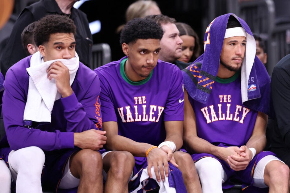 Oso Ighodaro, Ryan Dunn, and Devin Booker of the Phoenix Suns look on from the bench