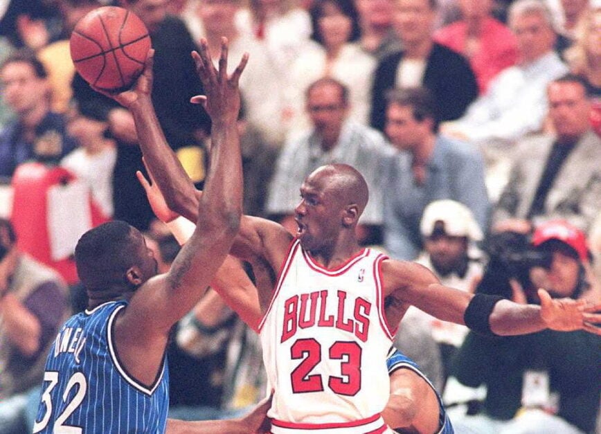 Michael Jordan of the Chicago Bulls (R) passes the ball off under pressure from Orlando Magic center Shaquille O'Neal (L) during the 1995 NBA Playoffs.
