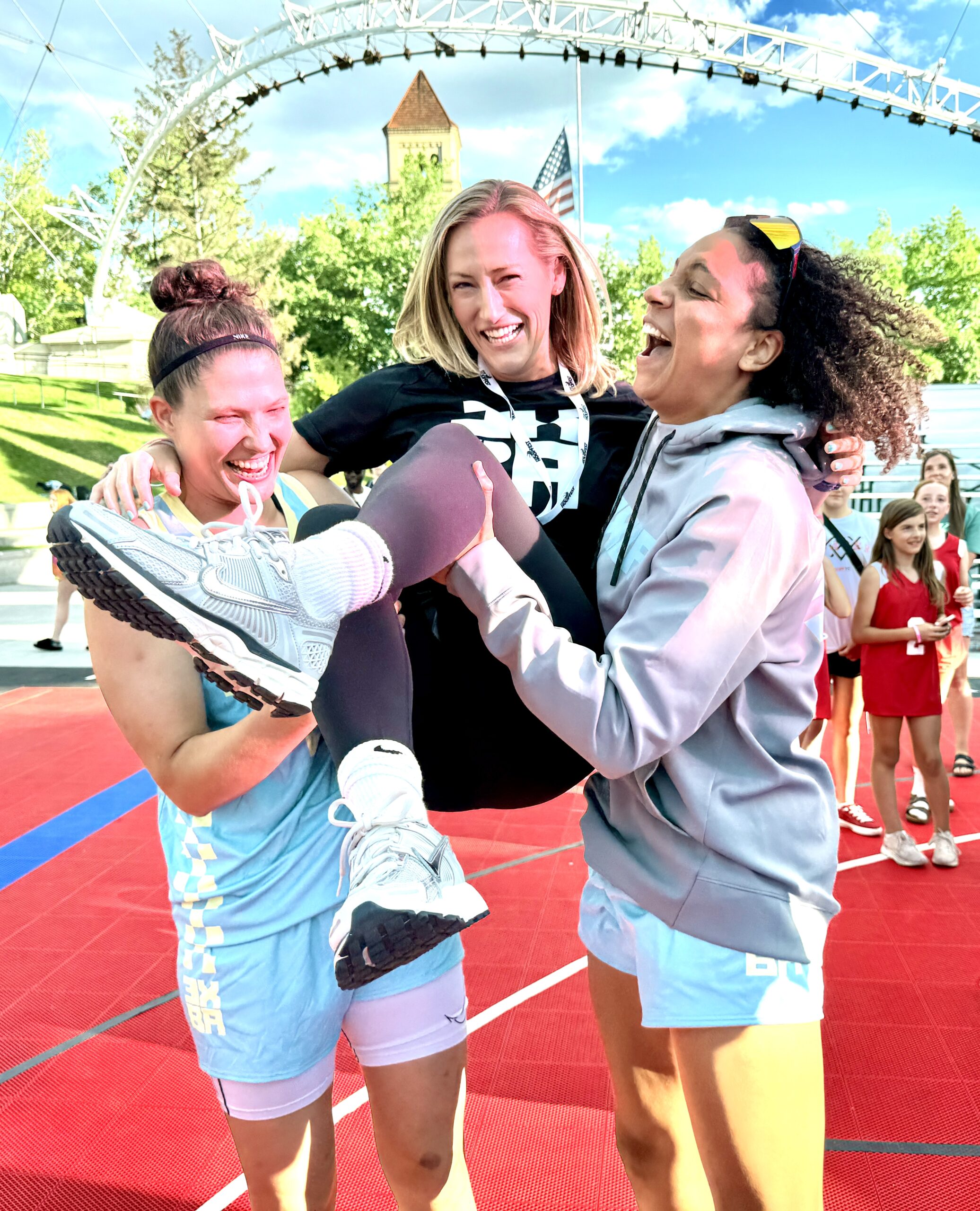 Two basketball players lift up 3XBA CEO Alanna McDonald at the conclusion of the 3SBA tournament in Spokane, WA on June 28, 2025. (Photo Credit: Steve Silverman | The Next)
