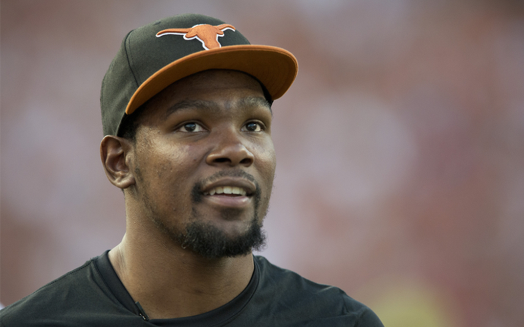 Man wearing a black cap with an orange brim and longhorn emblem.